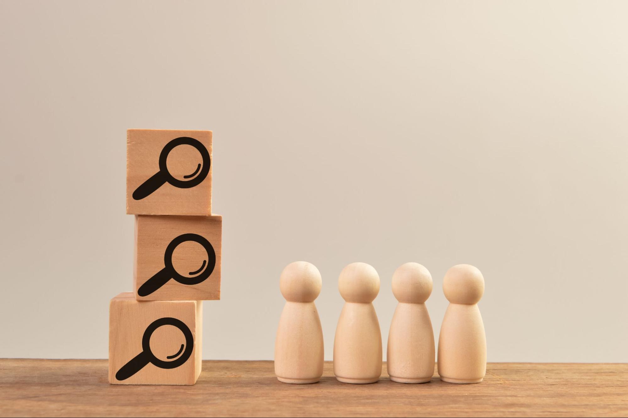 wooden figures in line, blocks with magnifying glass, representing search engine ranking